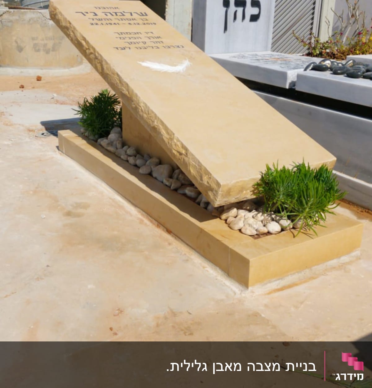 מצבה עם כיתוב בעברית ואבנים מסביב